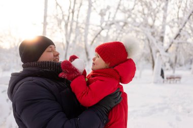 Mutlu baba kızını kırmızı bir ceketle kollarında tutuyor. Yakın plan. Çocuklar ve ebeveynler tatilde. Boşluğu kopyala.