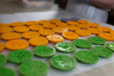 Silikon bir paspasın üzerinde fırında yeşil ve turuncu badem kurabiyeleri. Yemek pişirme süreci. Sığ odak