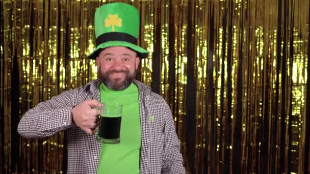 Koboldmännchen mit einem großen grünen Shamrock-Hut feiert den Vatertag. Er hält ein Glas Green Ale in den Händen und lächelt. Kopierraum. — Stockvideo