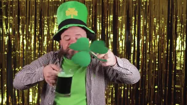 Homme barbu caucasien tient un verre de bière verte dans sa main et le trèfle inhale l'arôme et jouit. Concept de célébration de la Saint Patrick. — Video