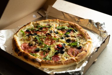 Folyodaki teslimat kutusunda zeytinli, salamlı ve peynirli lezzetli pizza. Un ürünleri ve aşırı kilolara karşı mücadele.