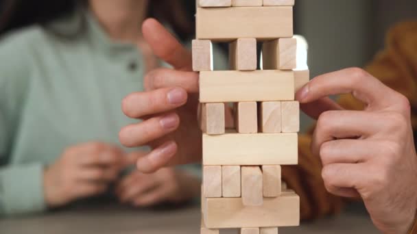 Van mannelijke handen trekken houten blok jenga spel. Toren gemaakt van houten blokken en menselijke handen nemen een blok — Stockvideo