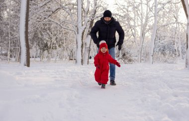 Yakışıklı genç bir baba ormanda karda koşar ve üç yaşındaki kızına yetişir. Kışın ailemle tatile çıkacağım..