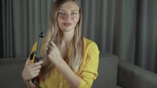 Joven hermosa mujer caucásica blogger de belleza en la habitación rizando su pelo largo con rulos y sonriendo. Mira la webcam. — Vídeo de stock