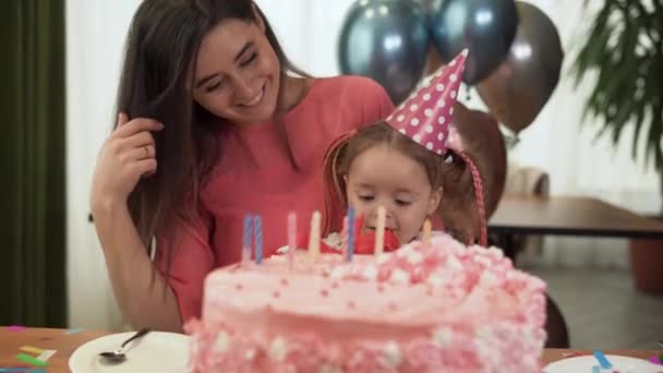 Anya és lánya otthon ülnek az asztalnál, és ünneplik a születésnapjukat. A lány kezében egy piros doboz.. — Stock videók