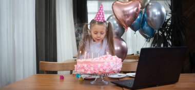 Bir kız doğum gününü internetten karantina zamanında kutluyor. Doğum günü pastasındaki mumları dizüstü bilgisayarın yanında söndürür. Şölen dekoru, tatlılar, balonlar. Ebeveynleri ve çocukları olan kızlar partisi.