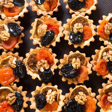 Kurutulmuş kayısı, kuru erik ve cevizle doldurulmuş lezzetli kısa hamurlu tartlar. Kurutulmuş meyve ve fındıklı sepetler. Sağlıklı bir tatlı. Yukarıdan görüntüle.