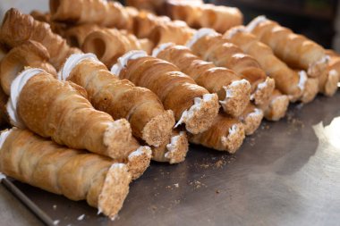 Metal bir tahtanın üzerinde pudra şekeri serpiştirilmiş protein ve muhallebi ile puf börekleri uzanır. Pastanenin mutfağında puf böreği var..