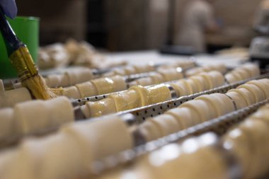 Metal bir koninin üzerindeki çiğ puf börekleri bitkisel yağla kaplanır. Bir pastanede yemek pişirmek. Fırın ve un ürünleri..