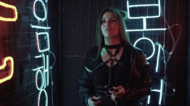 Güzel genç beyaz bir kadın neon lambaların yanında duruyor. Moda gözlüğü takıyor ve kameraya bakıyor. Şık kadın deri ceketi. Boşluğu kopyala.