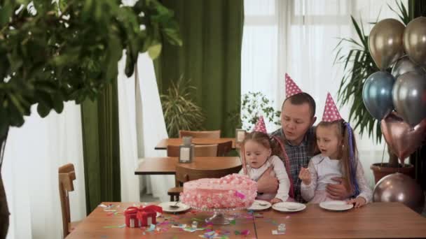 Cumpleaños familiar en casa, papá y dos hijas están sentadas en la mesa. Mamá cortó el pastel con un cuchillo afilado. — Vídeo de stock