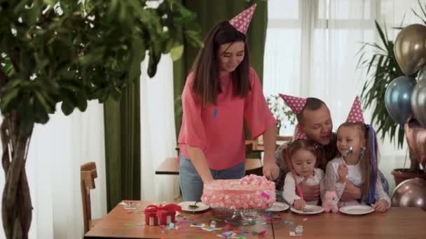 Vrolijke familie die een feestje geeft. Gelukkige ouders en kinderen vieren hun verjaardag binnen. De moeder snijdt de verjaardagstaart.. — Stockvideo