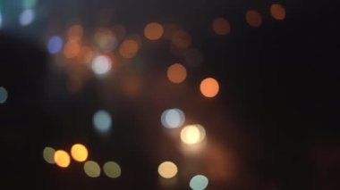 Gecenin karanlığında bulanık bir arka planda güzel, ışıl ışıl bir bokeh. Şehir caddesindeki araba farlarından yuvarlak renkli bokeh parlıyor.