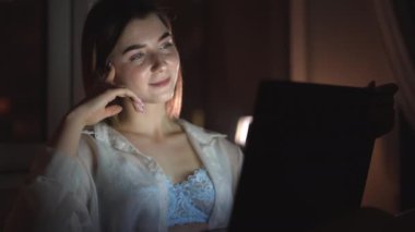 Geceleri evde tek başına oturan güzel beyaz bir bayanın yakın plan portresi. Bilgisayarla internetten bir video görüşmesi yapıyor. Boşluğu kopyala.
