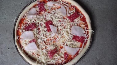 Masada peynir ve salamlı çiğ pizza vardı. Boşluğu kopyala.