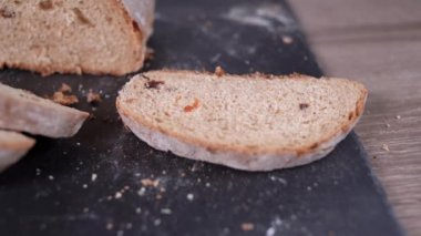 Kuru üzümlü çavdar ekmeğinin yakın plan çekiminde bir adamın eli yayılır. Boşluğu kopyala.