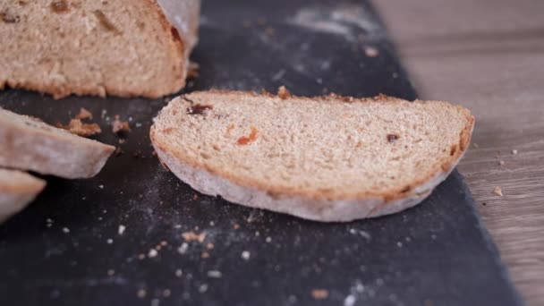 Κοντινό πλάνο μιας φέτας ψωμί σίκαλης με σταφίδες, το χέρι ενός άντρα πασαλείβει ένα πιάτο. Αντιγραφή χώρου. — Αρχείο Βίντεο