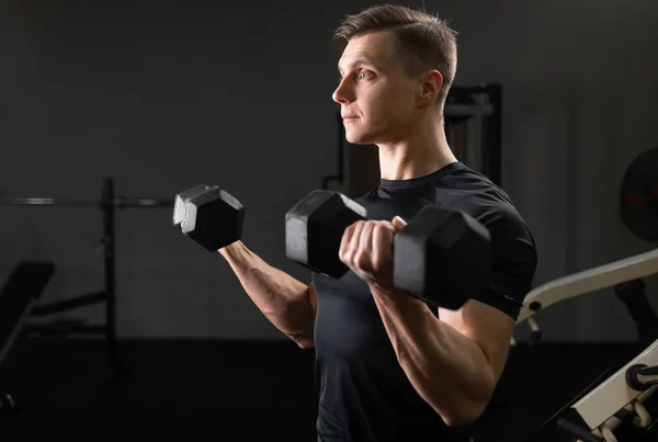 Joven guapo haciendo ejercicio en el gimnasio con pesas de metal de 10-20 kg. Giramos bíceps y tríceps con nuestras manos. —  Fotos de Stock
