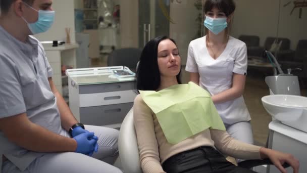 Genç beyaz kadın diş kliniğinde bir sandalyede oturuyor. Hastanedeki bir hastanın muayenesine hazırlanıyorum. Dişçi hastayı muayene etmeye hazırlanıyor.. — Stok video