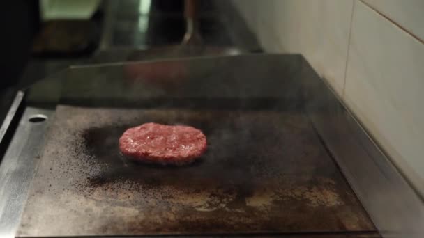 Cozinhar costeletas deliciosas e suculentas para um hambúrguer. Um grande pedaço de carne é grelhado no fogão. — Vídeo de Stock