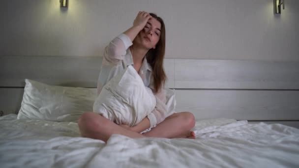 Droevige bedachtzame jonge blanke eenzame vrouw met een duur gezicht, knuffelend kussen zittend op bed denkend aan problemen, alleen thuis zittend, overstuur vrouwen die zich depressief voelen, — Stockvideo