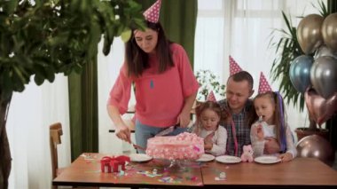 Neşeli bir aile parti veriyor. Mutlu ebeveynler ve çocuklar doğum günlerini evde kutlarlar. Annem doğum günü pastası yapıyor..