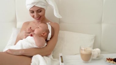 Çekici genç bir anne, küçük oğlu ya da kızıyla rahat bir yatakta yastıkla dinleniyor. Mutlu bir aile sabahı keyifle geçiriyor, olumlu duygulara sahip..