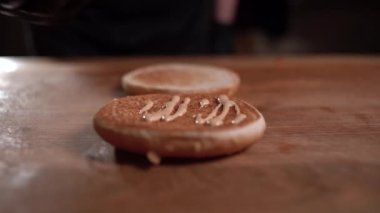 Şef bir hamburger hazırlar. Yakın plan - bir adam hamburger için kızarmış burgerin üzerine el sürme sosu sürer..