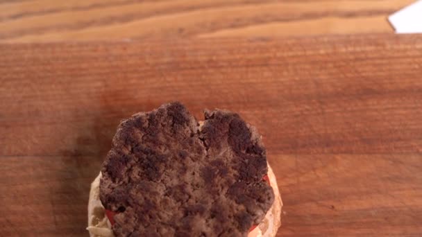 Vista de cerca de un chef profesional que prepara deliciosas y jugosas hamburguesas en un restaurante de comida rápida. Un chef con guantes pone queso en una hamburguesa frita. — Vídeos de Stock