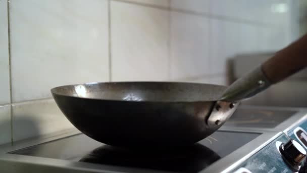 Сковородка на плите, человек в черной перчатке бросает в нее лапшу. — стоковое видео