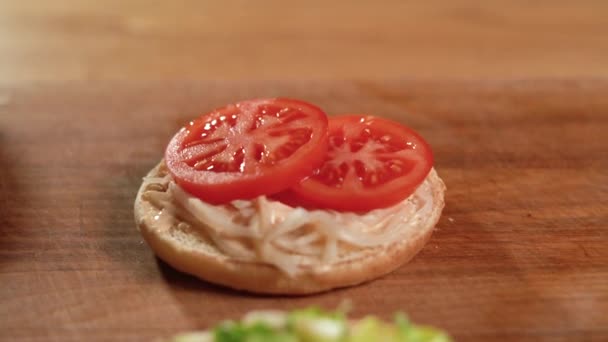 Vegetariánský burger leží na stole, nakládaná cibule a rajčatové plátky. — Stock video