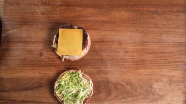 Fast food restoranında hamburger yapıyorum. Erkek eli kızarmış ekmeği kaplıyor. Yakın plan. Lezzetli burger yemeye hazır..