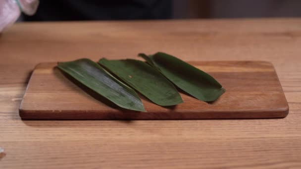 Крупным планом рук поваров, лежащих на пальмовых листьях суши рулон с тунцом. — стоковое видео
