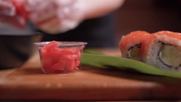Primo piano di mani di chef che mettono lo zenzero messo sotto aceto in un piatto disponibile. — Video Stock