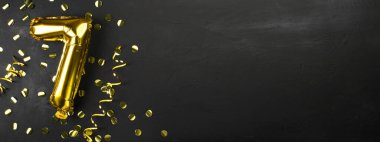 Yedi ya da yedi numaralı altın folyo balonu. Üzerinde yedi siyah beton arkaplan yazan doğum günü tebrik kartı. Yıldönümünü kutluyoruz. Pankart. Boşluğu kopyala