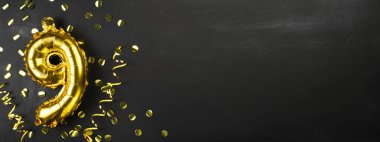 Altın folyo balonu dokuz ya da dokuzuncu. 9. yazılı doğum günü tebrik kartı. Siyah beton arka plan. Yıldönümünü kutluyoruz. Pankart. Boşluğu kopyala