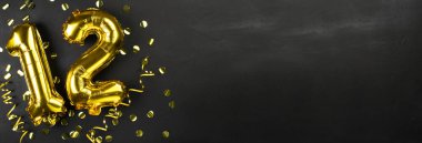 12 numaralı altın folyo balonu. 12 yazılı doğum günü ya da yıldönümü tebrik kartı. Siyah beton arka plan. Yıldönümü kutlaması. Pankart. Boşluğu kopyala
