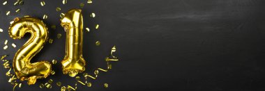 Altın folyo balonu 21 numara. Doğum günü ya da yıldönümü tebrik kartı, üzerinde 21 yazılıydı. Siyah beton arka plan. Yıldönümü kutlaması. Pankart. Boşluğu kopyala