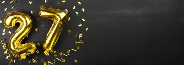 27 numaralı altın folyo balonu. Doğum günü ya da yıldönümü tebrik kartı 27 yazılıydı. Siyah beton arka plan. Yıldönümü kutlaması. Pankart. Boşluğu kopyala