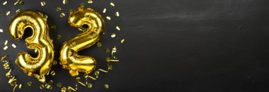 32 numaralı altın folyo balonu. Doğum günü ya da yıldönümü kartı 32 yazılıydı. Siyah beton arka plan. Yıldönümü kutlaması. Pankart. Boşluğu kopyala