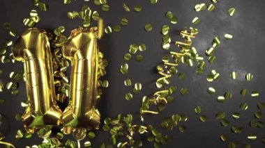 Altın folyo balon numarası 11. Doğum günü ya da yıldönümü tebrik kartı. Üzerinde 11 yazılıydı. Siyah beton arka plan. Yıldönümü kutlaması.