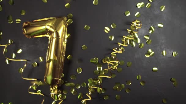 Foglio d'oro palloncino numero sette o settimo. Biglietto di auguri di compleanno con l'iscrizione 7. sfondo di cemento nero. Festeggiamo l'anniversario. — Video Stock