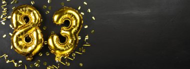 Seksen üç numaralı altın folyo balonu. 83 yazılı doğum günü ya da yıldönümü kartı. Siyah beton arka plan. Yıldönümü kutlaması. Pankart. Boşluğu kopyala