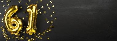 Altmış bir numaralı altın folyo balonu. 61 yazılı doğum günü ya da yıldönümü kartı. Siyah beton arka plan. Yıldönümü kutlaması. Pankart. Boşluğu kopyala