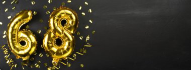 Altmış sekiz numaralı altın folyo balonu. Yaş günü ya da yıldönümü kartı 68 yazılıydı. Siyah beton arka plan. Yıldönümü kutlaması. Pankart. Boşluğu kopyala
