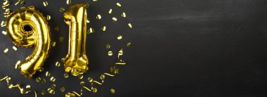 Doksan bir numaralı altın folyo balonu. Doğum günü ya da yıldönümü kartı 91 yazılıydı. Siyah beton arka plan. Yıldönümü kutlaması. Pankart. Boşluğu kopyala