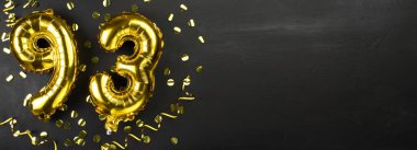 Doksan üç numaralı altın folyo balonu. Doğum günü ya da yıldönümü kartı 93 yazılıydı. Siyah beton arka plan. Yıldönümü kutlaması. Pankart. Boşluğu kopyala