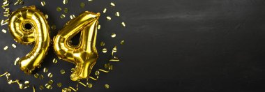 94 numaralı altın folyo balonu. Doğum günü ya da yıldönümü kartında 94 yazılıydı. Siyah beton arka plan. Yıldönümü kutlaması. Pankart. Boşluğu kopyala