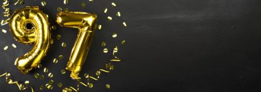 Doksan yedi numaralı altın folyo balonu. Doğum günü ya da yıldönümü kartı 97 yazılıydı. Siyah beton arka plan. Yıldönümü kutlaması. Pankart. Boşluğu kopyala