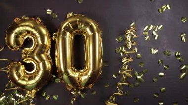 30 numaralı altın folyo balonu. Doğum günü ya da yıldönümü tebrik kartı, üzerinde 30 yazılıydı. Siyah beton arka plan. Yıldönümü kutlaması.